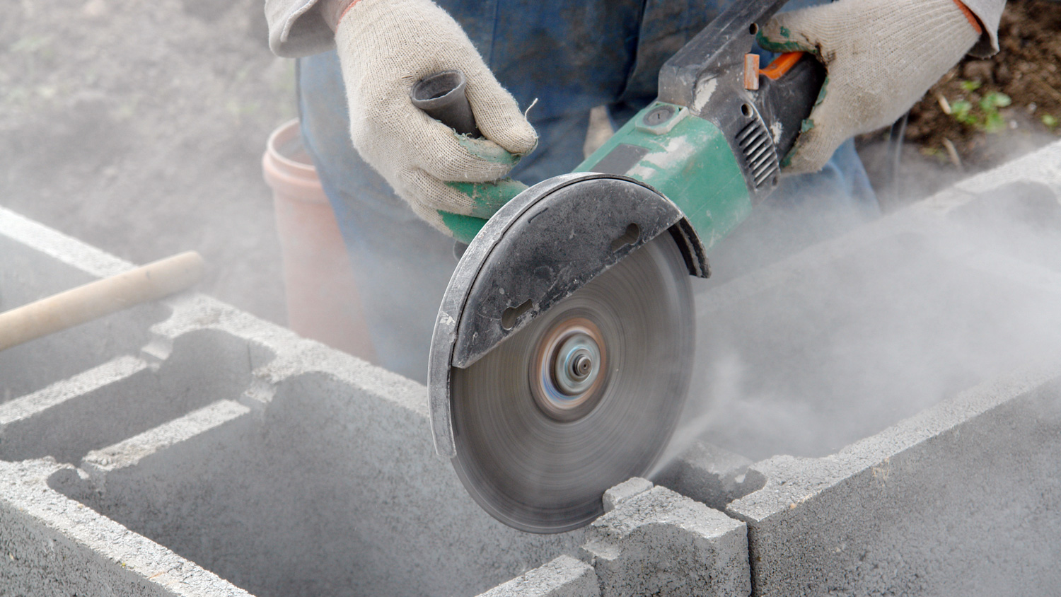 A worker grinding concrete causing dust