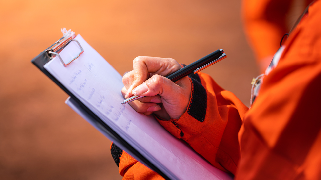 A health and safety inspector writes on a clipboard