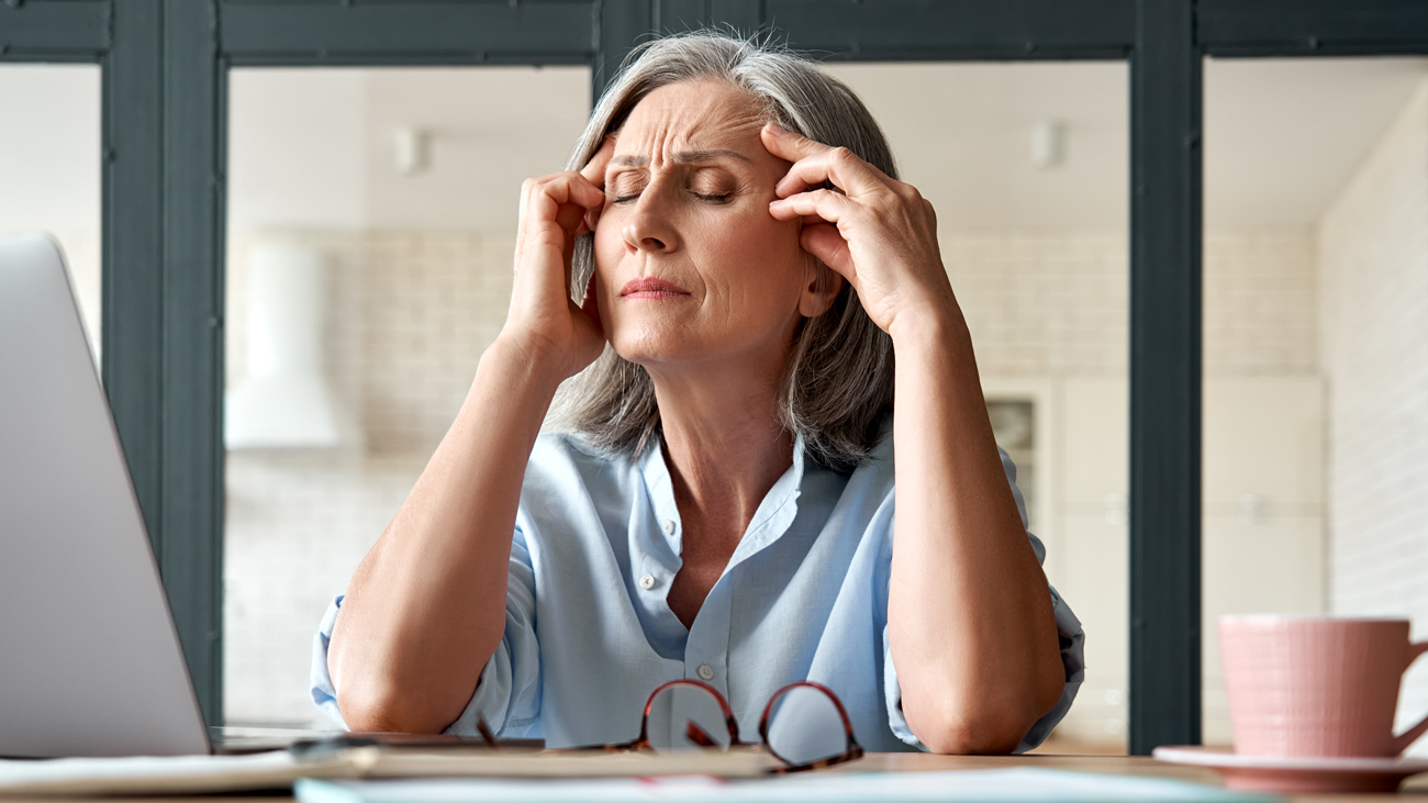 Menopausal or stressed woman holding her head
