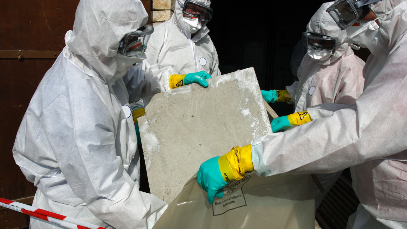 Workers in PPE remove asbestos-containing materials