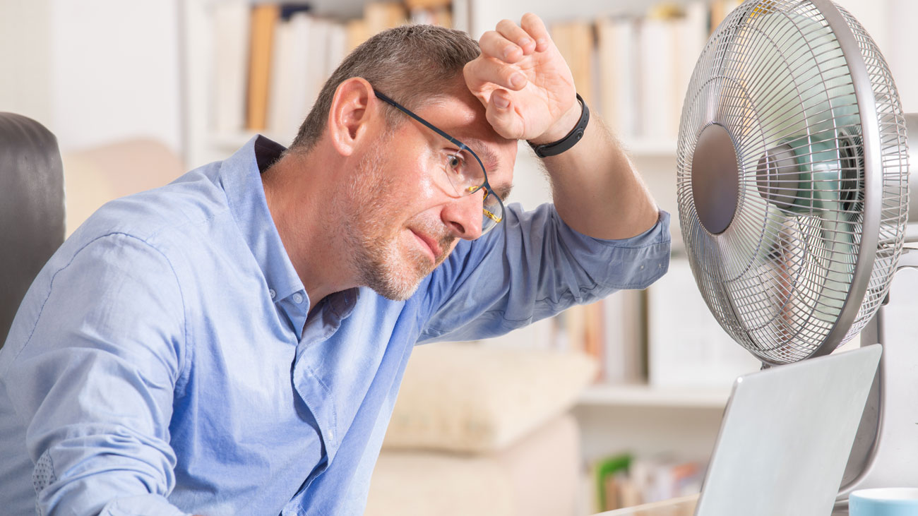 A hot employee sitting in front of a desk fan