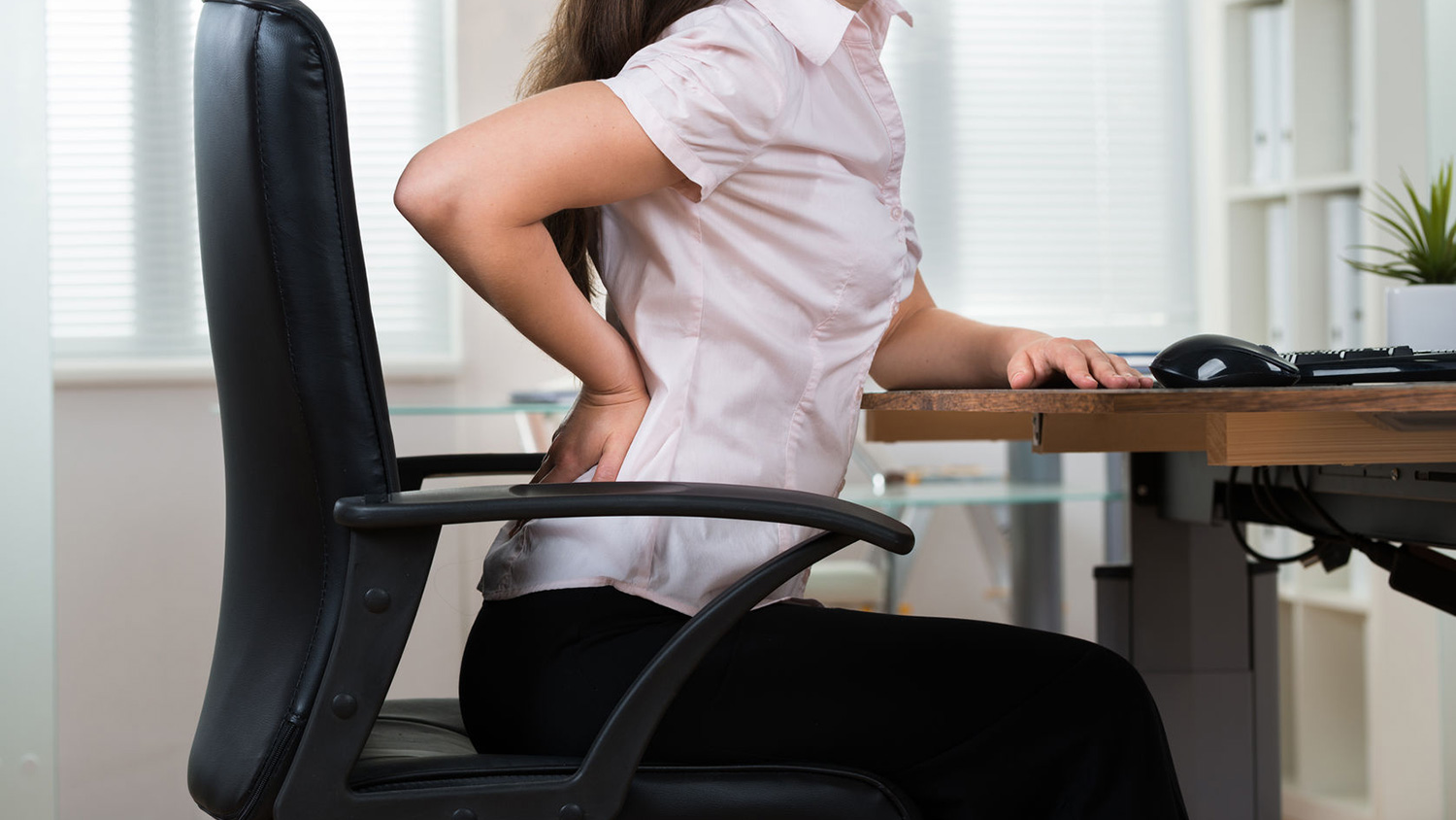 A woman with back pain sits on a chair