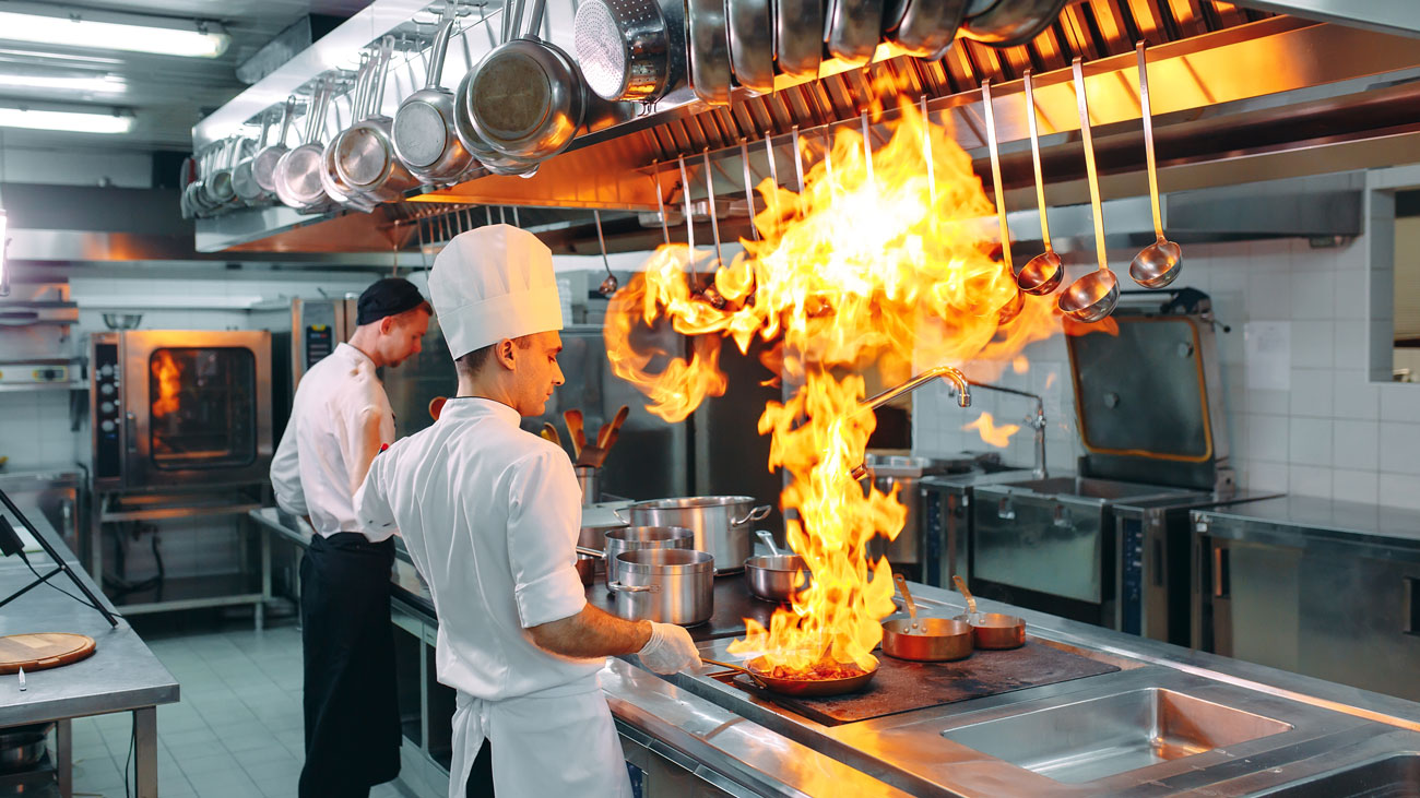 A chef works with a naked flame in a kitchen