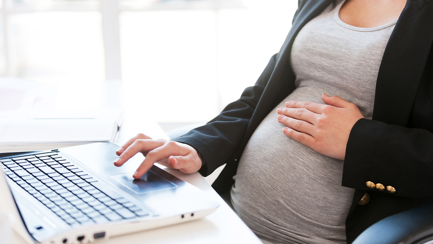 A pregnant woman sits at a desk