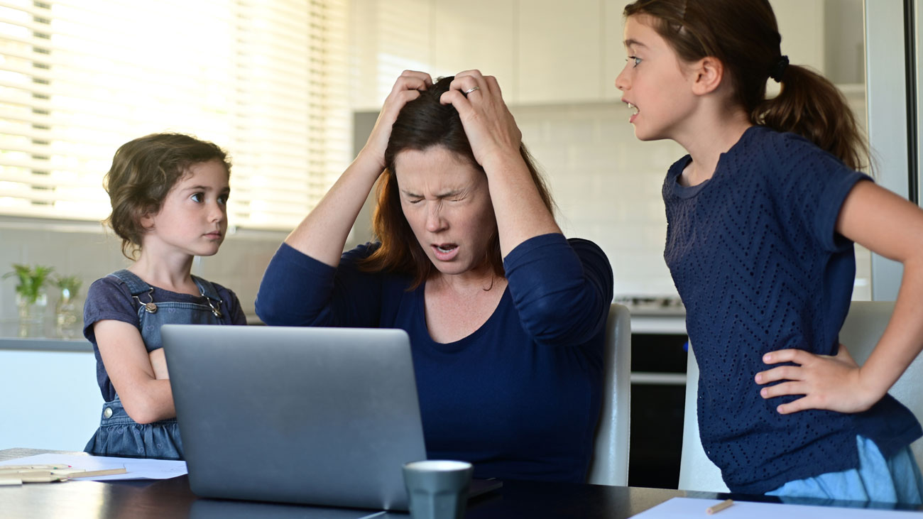 A woman working from home is stressed out by her children