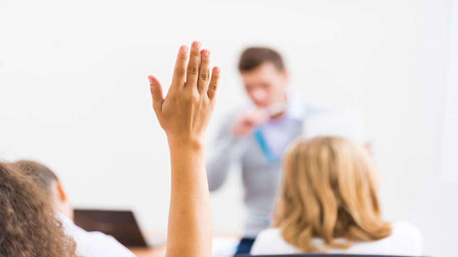 A student raises their hand in a classroom